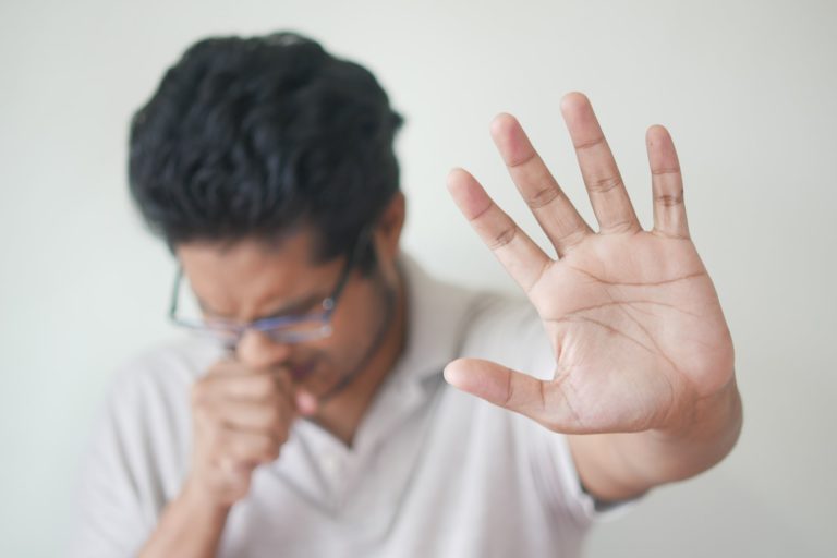 homem tossindo com a mão erguida aguardando tratamento