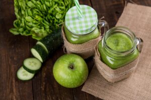 jarra de suco verde com óleos essenciais, pepino cortado e maçã inteira