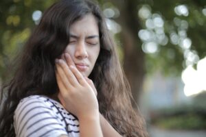 menina com dor de dente leva as mãos às bochechas